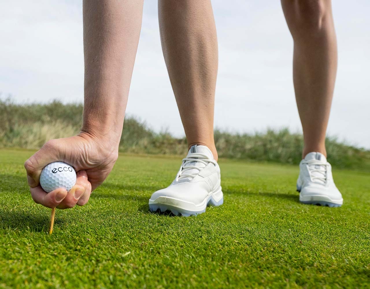 Woman teeing up golf ball