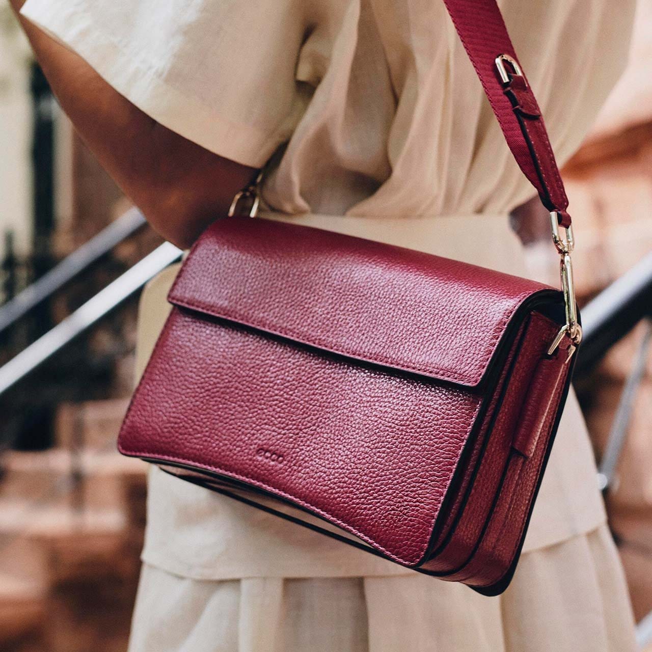 Woman holding red crossbody bag