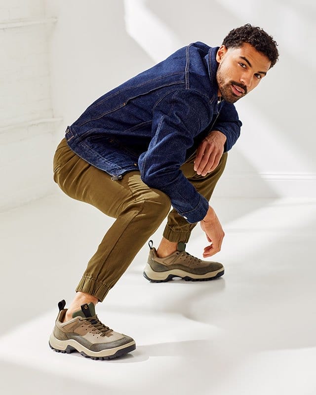 Model wearing denim jacket with tan pants and outdoor sneakers