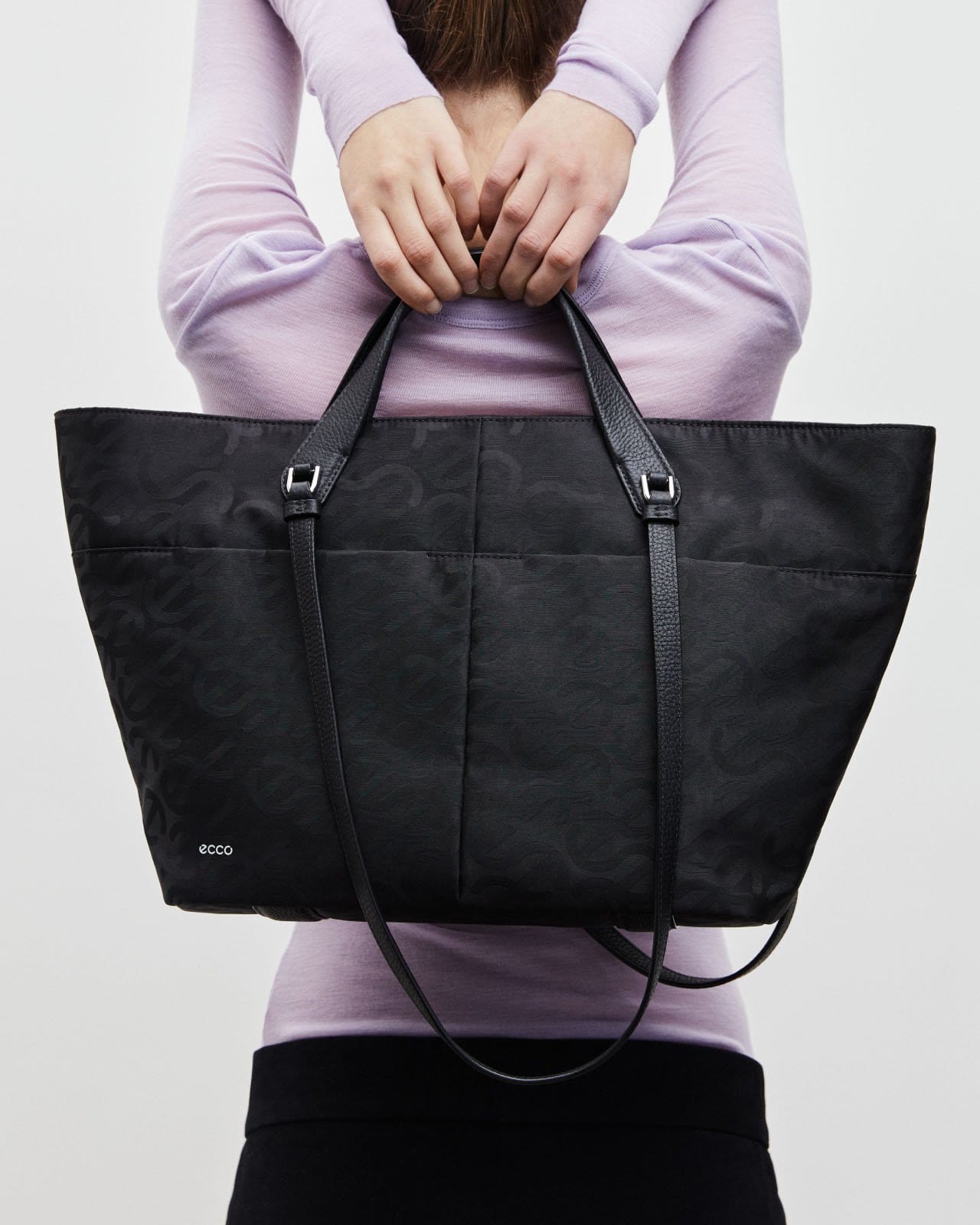 Woman holding black tote bag over her shoulders