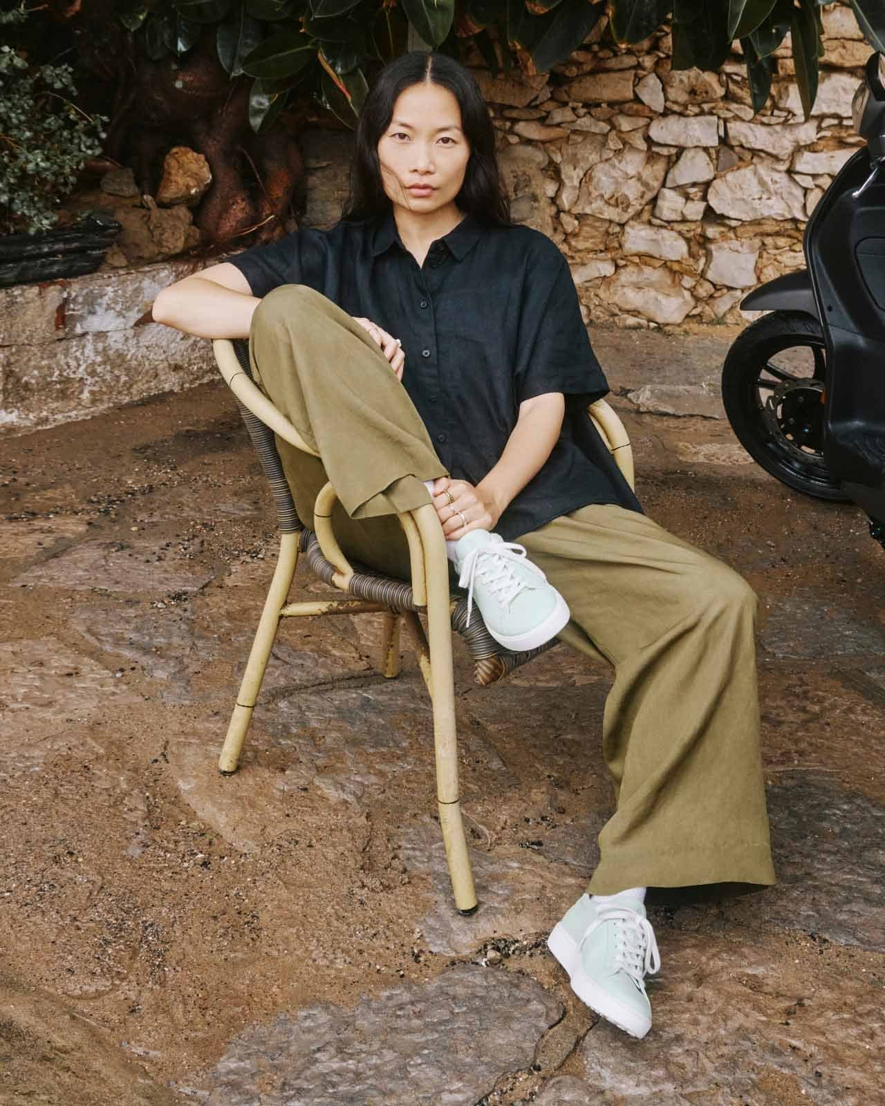 Woman sitting in chair outdoors wearing casual sneakers