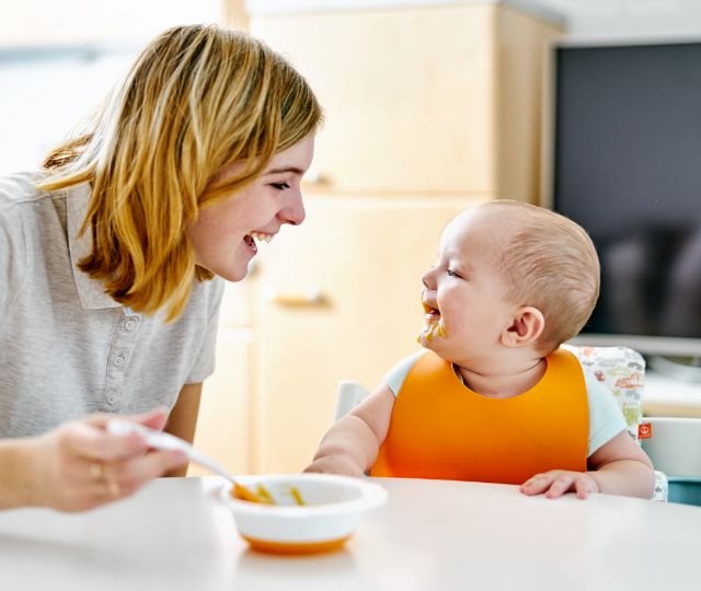 Mom spoon-feeding her child at the table