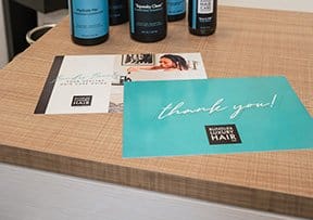 postcards designed as thank you cards sit on a desk top at Bundles Hair Company.