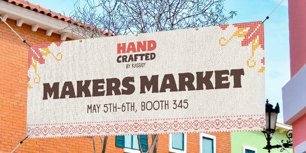 A vibrant outdoor banner hangs outside reading “MAKERS MARKET.”