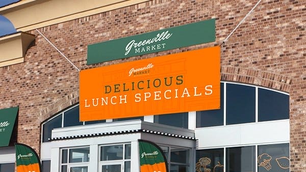 An outdoor banner inspires shoppers to try “DELICIOUS LUNCH SPECIALS” at The Greenville Market.