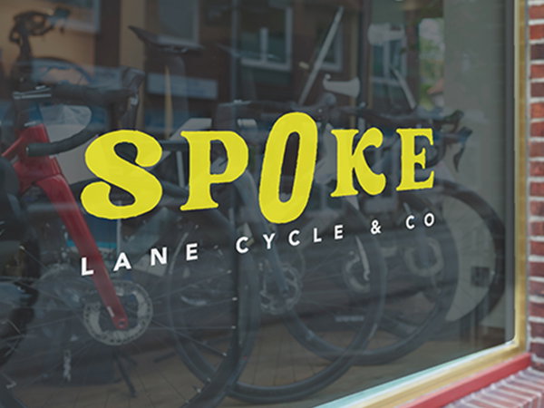 A window graphic on a bicycle shop window with crisp yellow lettering.