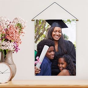 A photo tapestry featuring a mother in a graduation gown hangs on a wall. 