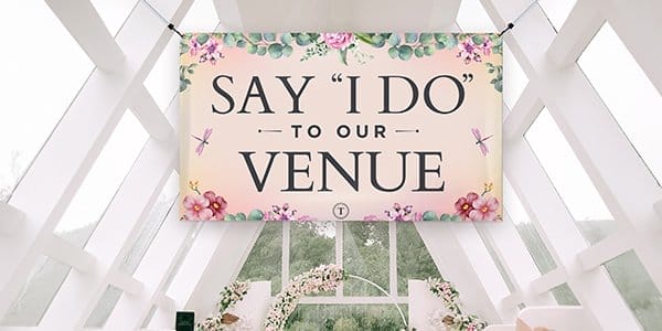 An indoor banner reads “SAY I DO TO OUR VENUE” and hangs on site at a wedding venue.