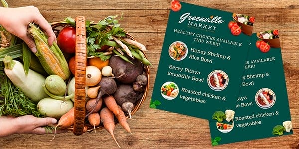 Two green menus next to a fresh bowl of vegetables show off the Greenville Market specials.