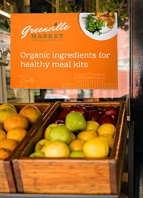 A styrene sign hangs above fresh produce spotlighting “organic ingredients for healthy meal kits.”