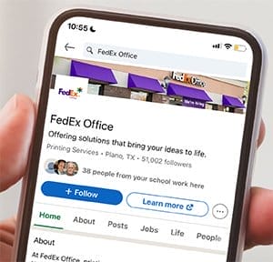 A hand holds a phone open to the FedEx Office LinkedIn page.