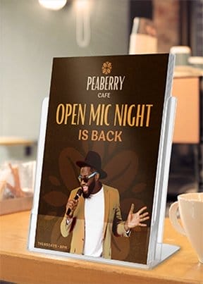 A brown flyer sits in a stand on a counter with an image of a singer holding a microphone and reads 'OPEN MIC NIGHT IS BACK.' 