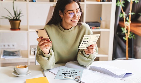 A happy woman reads her direct mail and sees the accompanying digital ads on her phone.