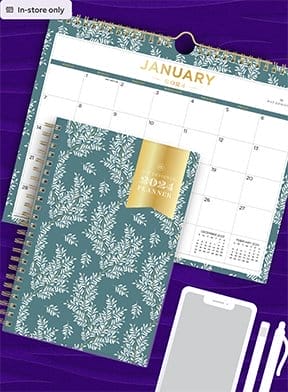 A colorful planner rests on top of a calendar that reads “JANUARY.” 