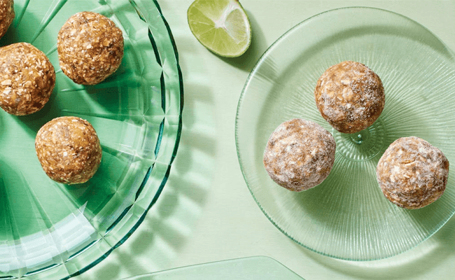 Two green-tinted glass plates with a few Key Lime Oat Bites on each. On one plate the bites are plain and on the other they are coated in finely granulated cane sugar