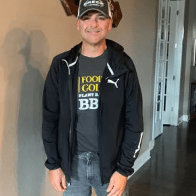 Brian Rodgers standing in his hallway wearing a baseball cap and an athletic jacket