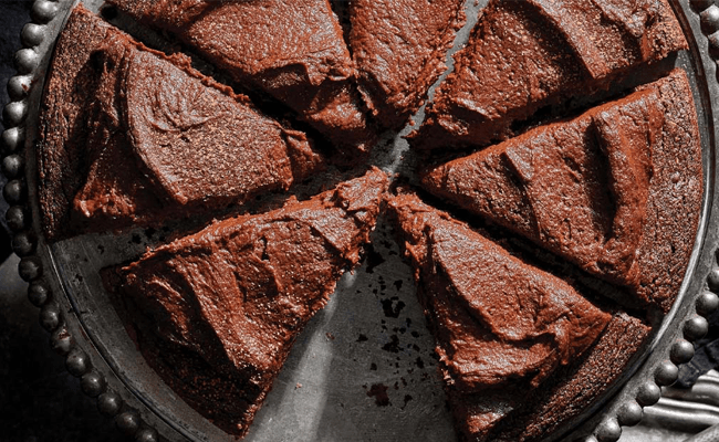 Incredible Chocolate Sweet Potato Cake on a silver cake platter, cut into eight slices, with one slice removed