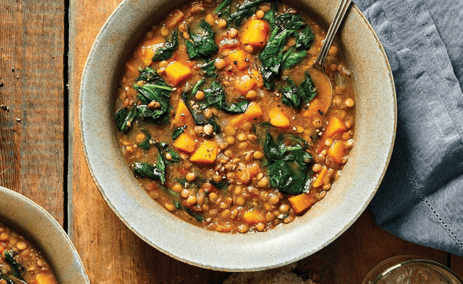 Lentil and Spinach Soup in a beige ceramic bowl on a wooden tabletop