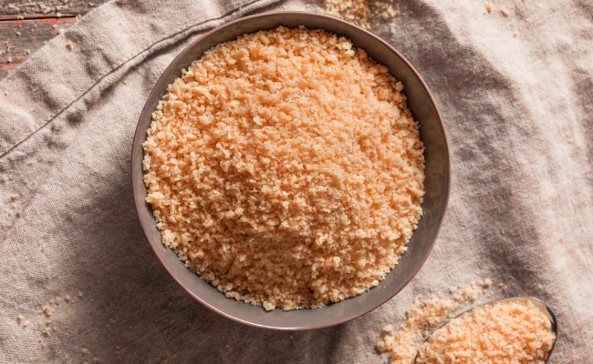 A bowl of whole wheat panko sitting atop a kitchen towel, shown from above