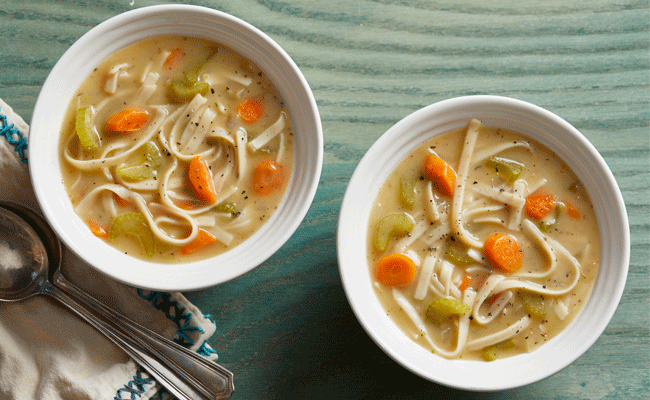 Two bowls of Quick and Easy Noodle Soup on a green background