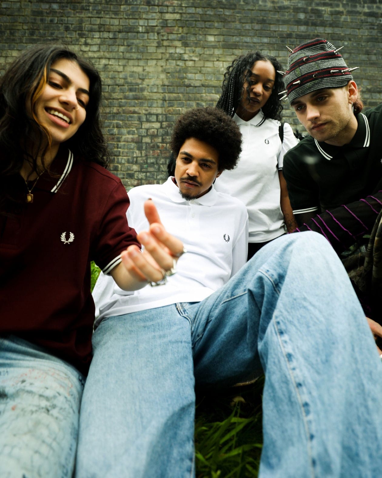 Group of young adults in an amusing discussion, wearing varied Fred Perry shirts in an urban setting