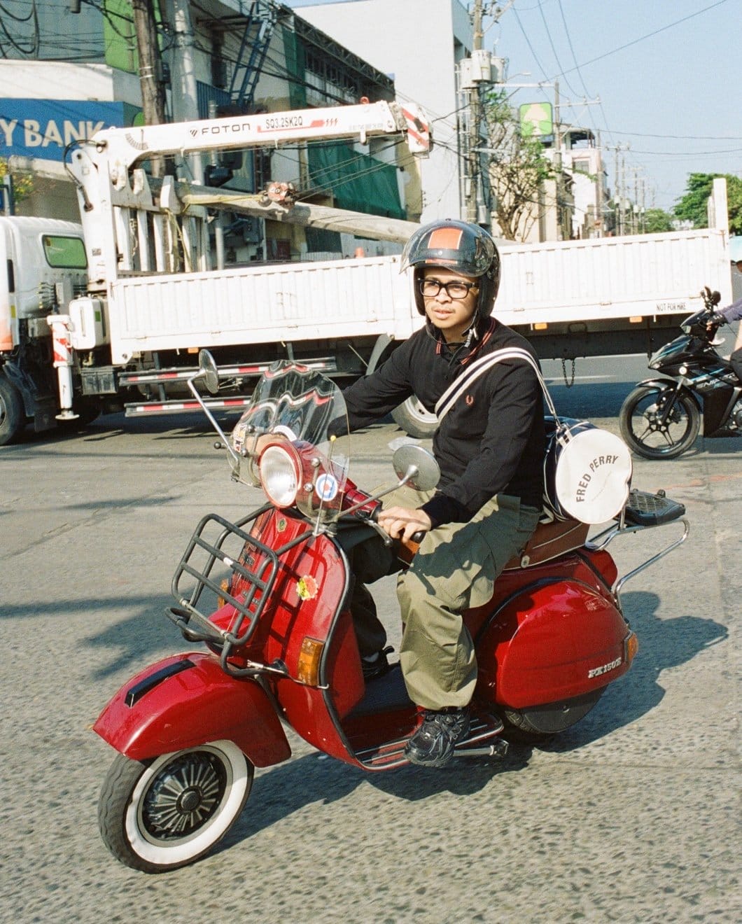 Man wearing navy long sleeved, twin tipped, Fred Perry Shirt on a red vespa 