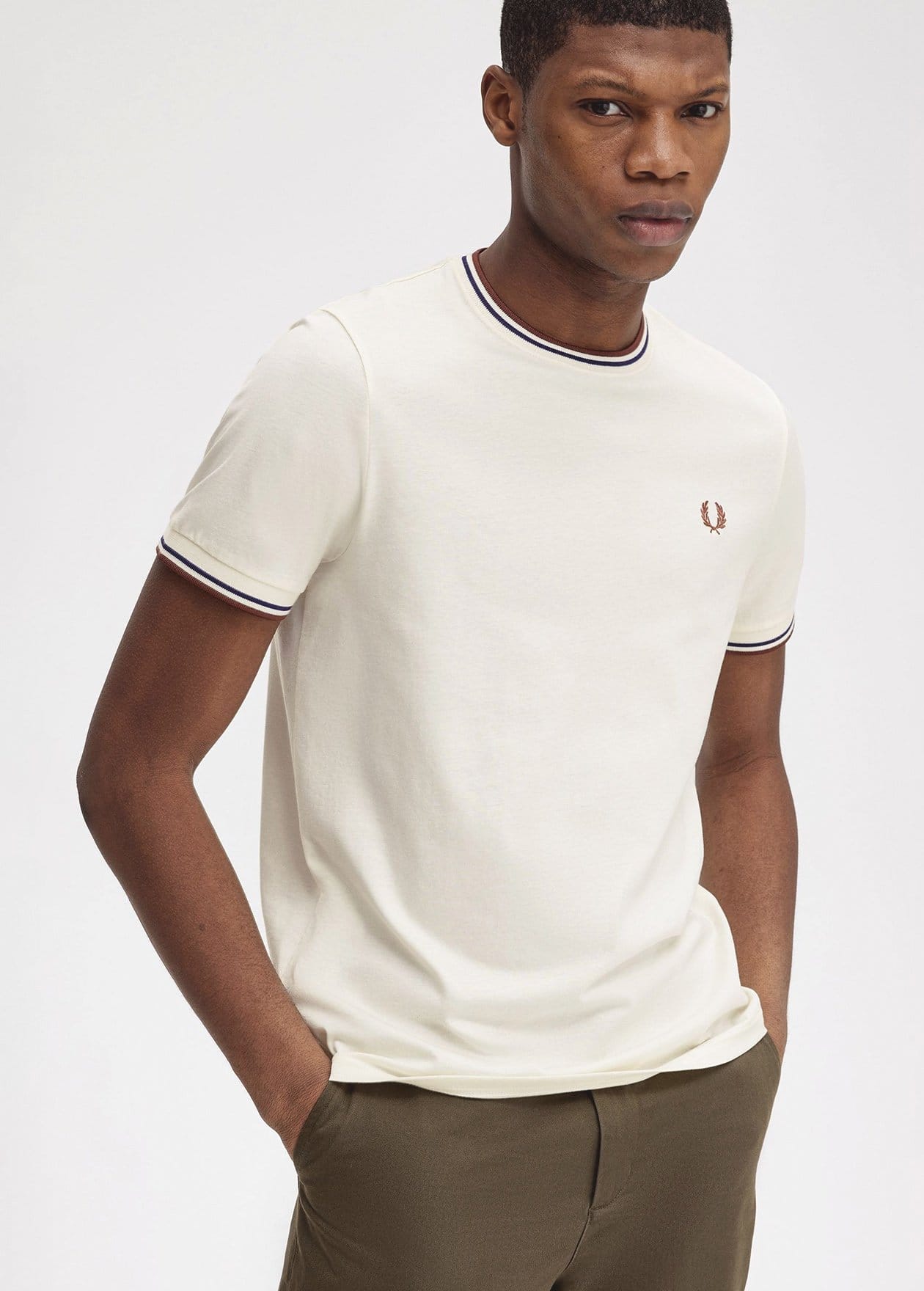 Man wearing an ecru coloured twin tipped fred perry t-shirt