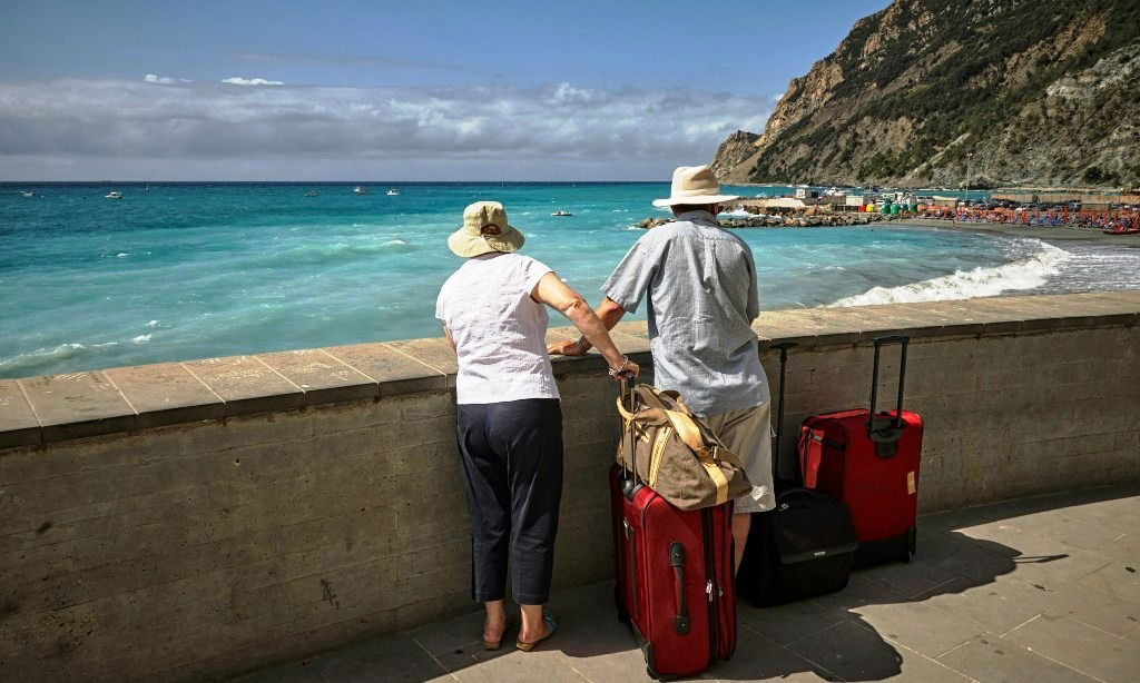 Couple with suitcases looking out over the sea