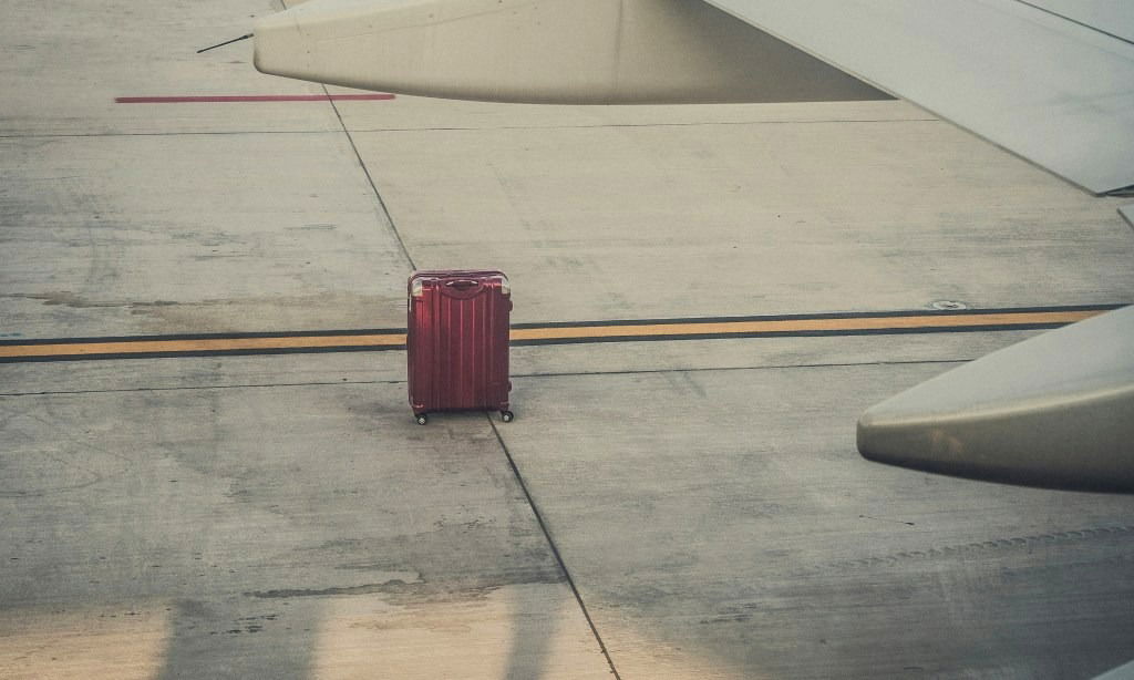 Suitcase sitting beneath a plane wing