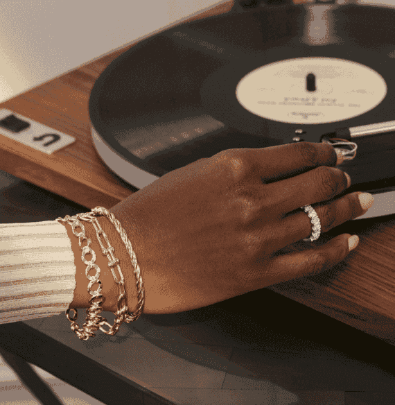 Close-up of a woman's hand, with stacked gold bracelets and diamond ring prominently displayed.