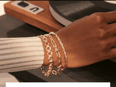 A women is seen adorned with multiple stunning golden bracelets.