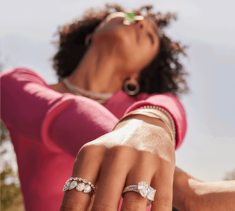 A woman adorned with stunning jewelry basks in the sun, with wedding rings prominently featured.