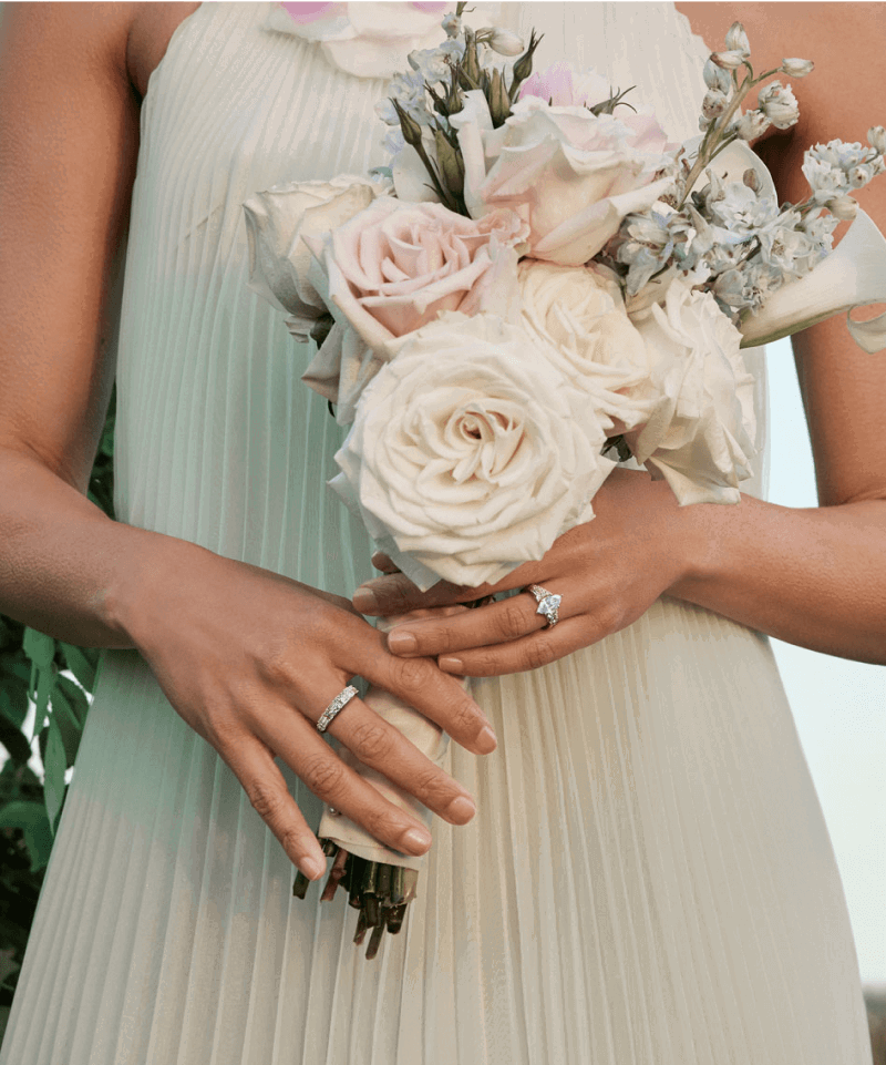 A bridesmaid poses with a bouquet of flowers, and stunning diamond rings