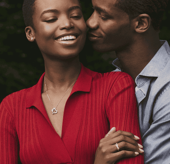 A couple share an affectionate moment. Assorted women's jewelry is visible, including a earrings, necklace, and ring.