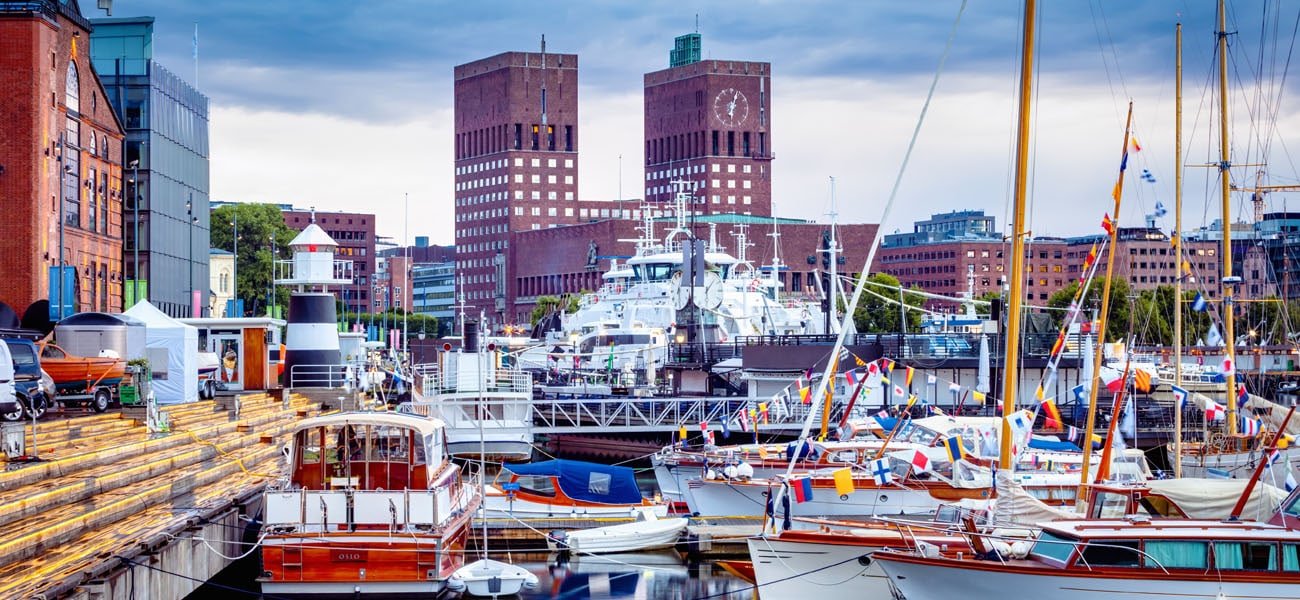 View of Oslo City Hall from Aker Brygge Marina in Oslo, Norway, with boats in the foreground.