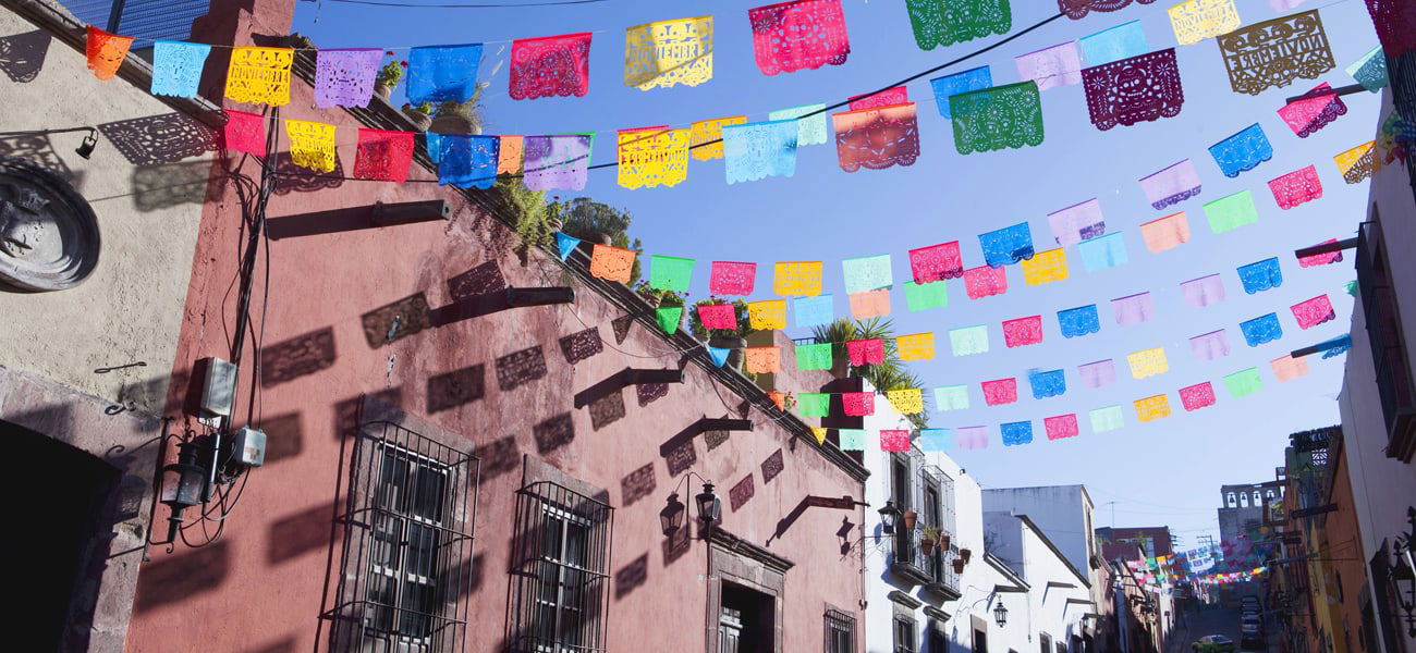 Colourful cut out paper flags hanging above a street.