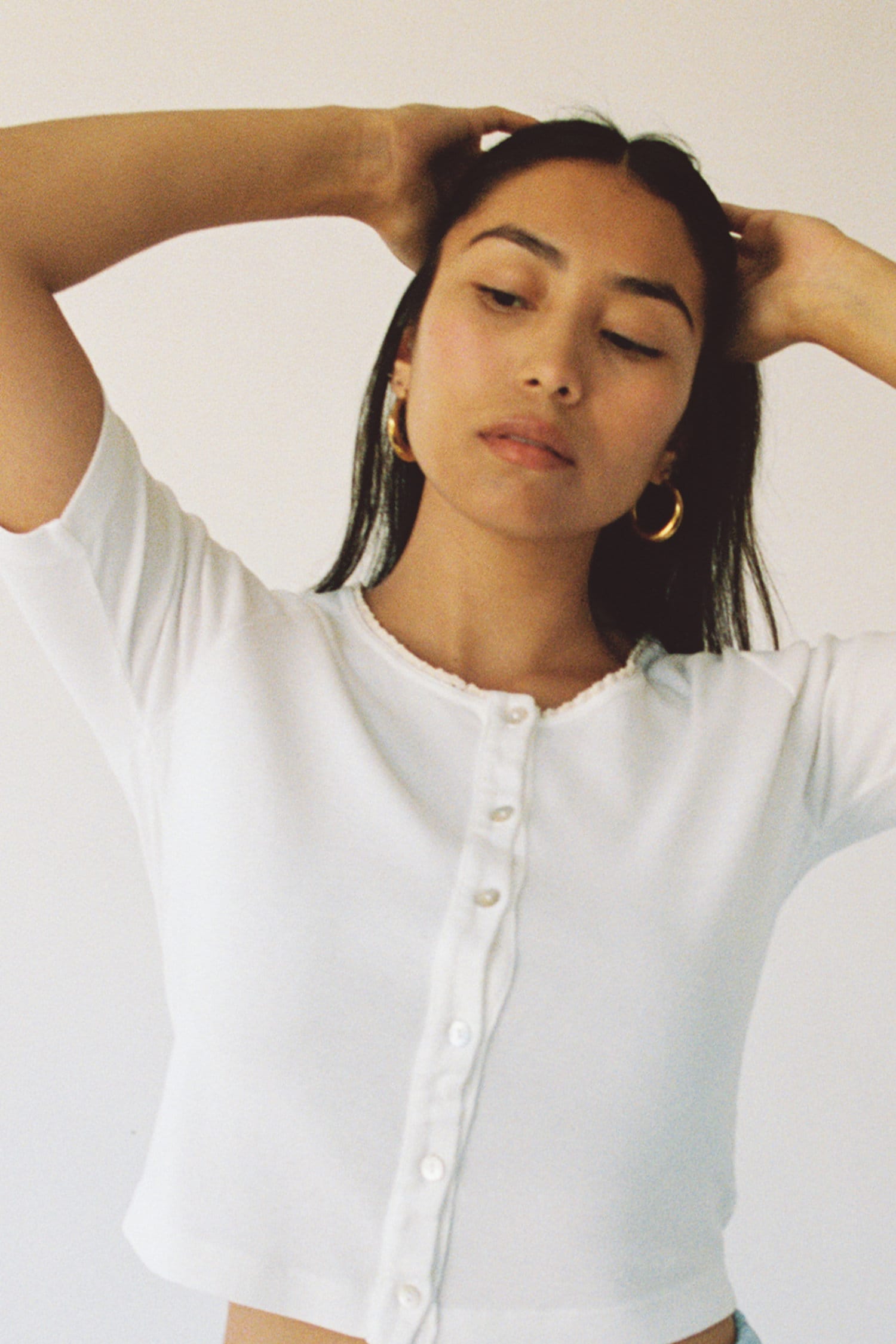 cropped view of a white button up tee on dark haired model.