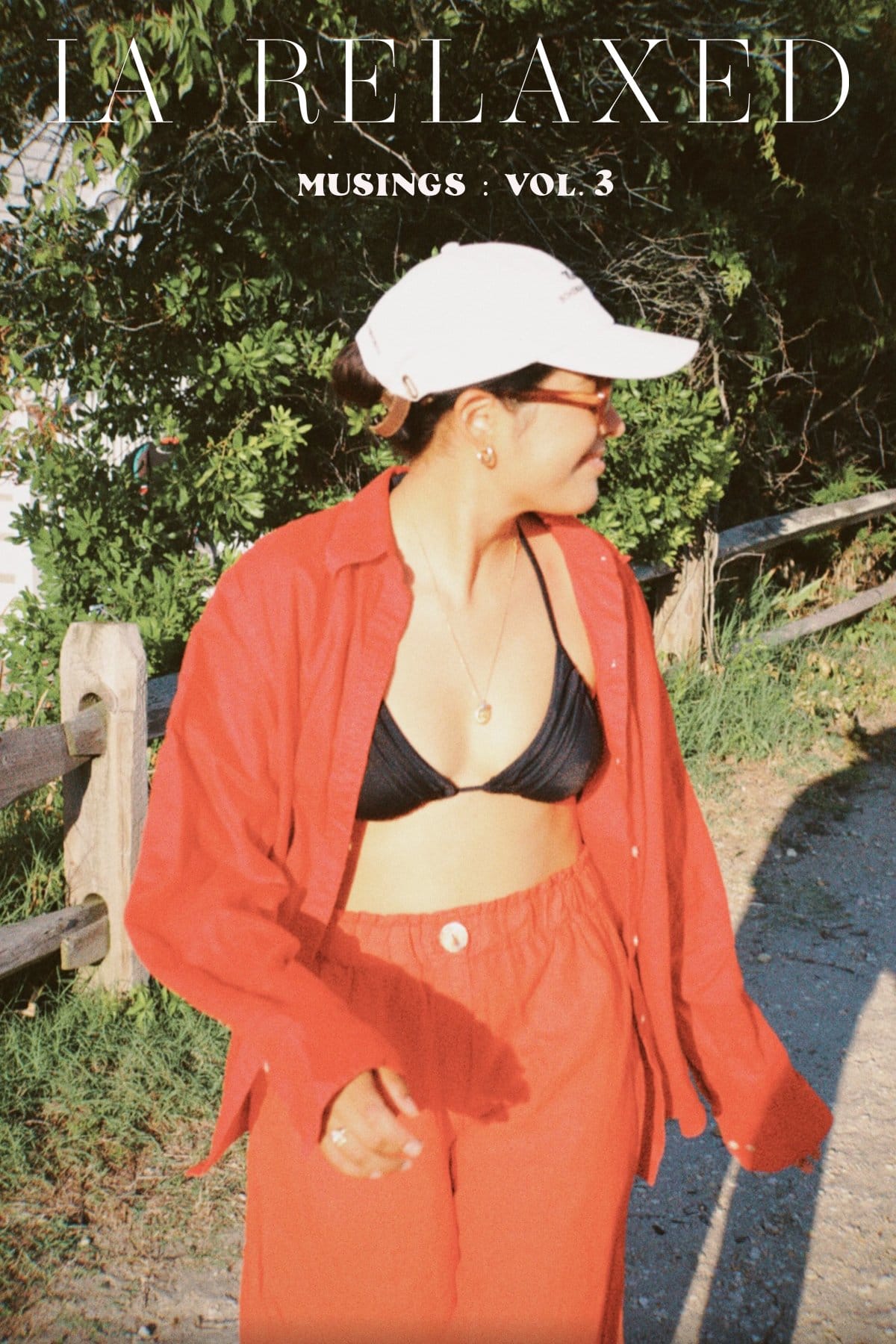 woman walks down sandy path in red linen set with black bikini top showing.