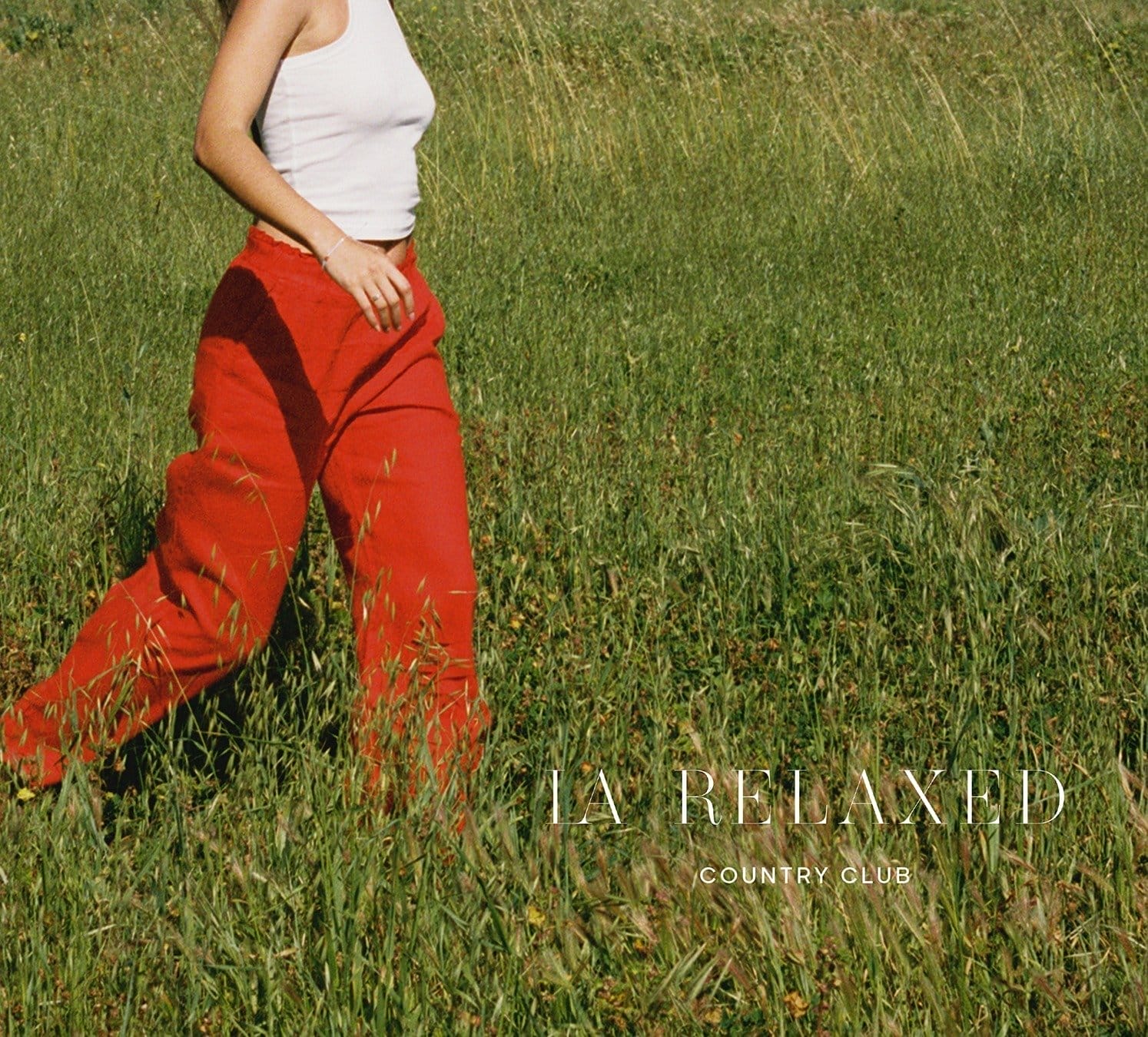 Cropped image of woman running through field in red pants.