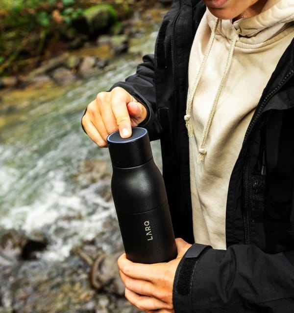 woman pressing button on the LARQ Bottle PureVis™ to purify water.