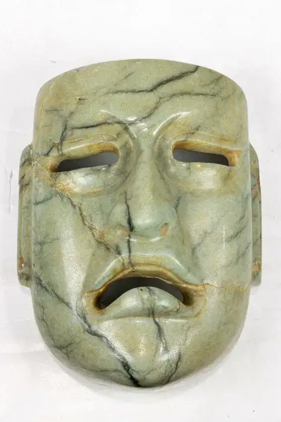 A Pre Columbian Olmec carved jade or hardstone face with early stabilized hairlines at fissures