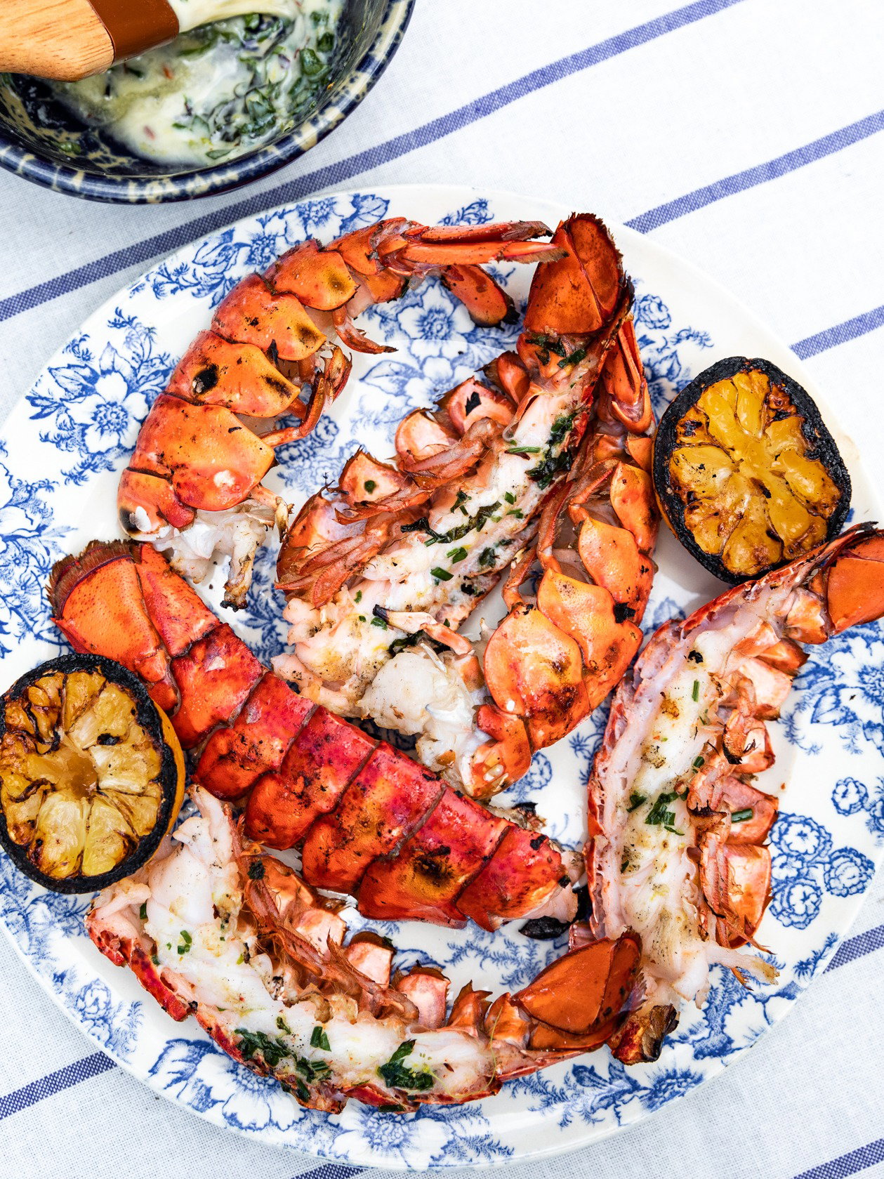 A plate of cooked split lobster tails with lemons