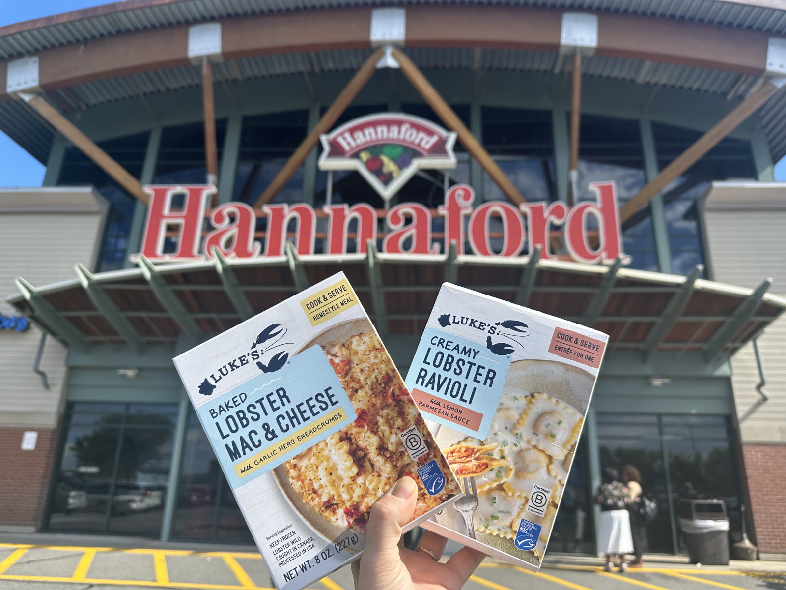 Holding a package of Luke's Lobster Lobster Ravioli and Lobster Mac & Cheese in front of Hannafords Supermarket