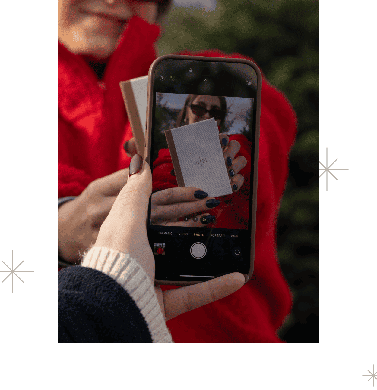 A woman taking an iphone photo of another woman holding up a mbm box.