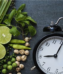 analog alarm clock next to green produce