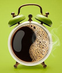 analog alarm clock that looks like a cup of coffee on a green background