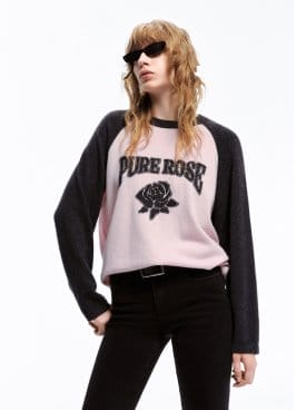 a model wears a sweater and black pants with a t shirt and sunglasses