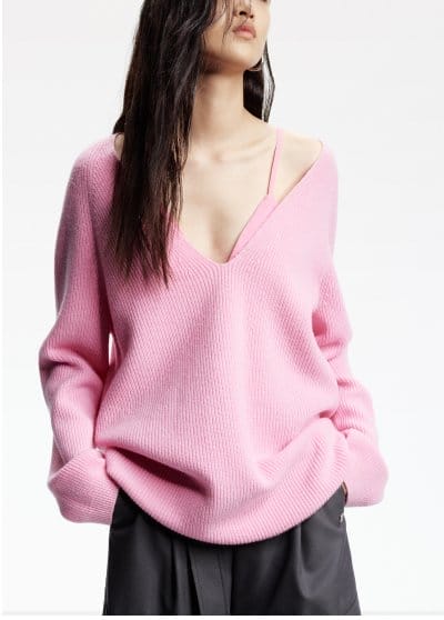 a woman is wearing a pink sweater and a black skirt