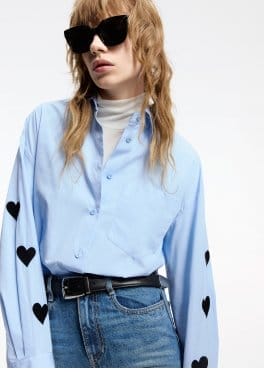 a woman wearing a blue shirt with hearts on it