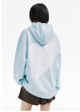 a woman wearing a light blue hoodie with a heart on it